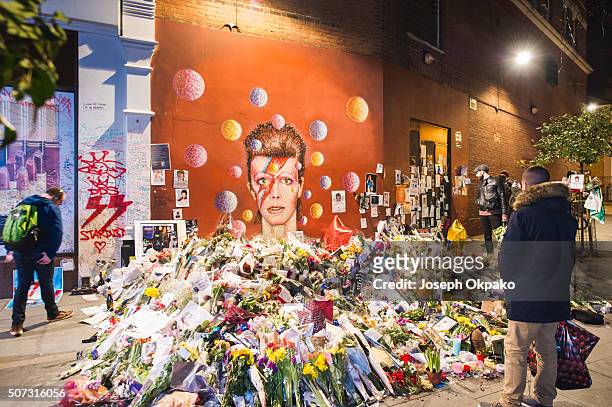 People pay their respect near the tribute mound which continues to grow two weeks after the death of Brixton born English singer, songwriter David...