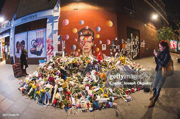 People pay their respect near the tribute mound which continues to grow two weeks after the death of Brixton born English singer, songwriter David...