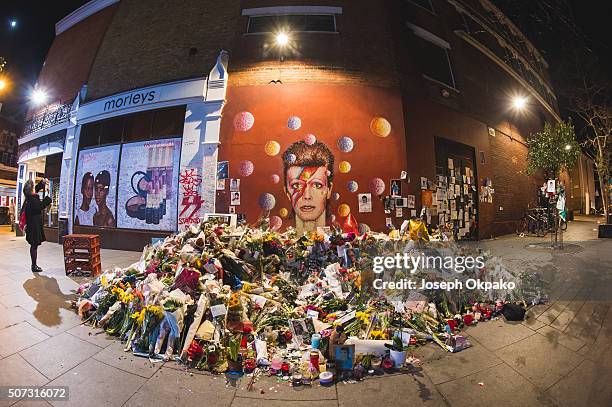 People pay their respect near the tribute mound which continues to grow two weeks after the death of Brixton born English singer, songwriter David...