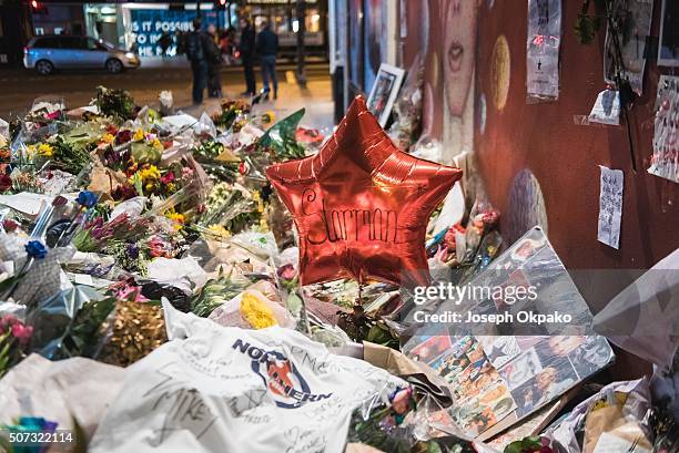 Close up details of Flowers, letters and other tributes left on a mound continue to grow two weeks after the death of Brixton born English singer,...