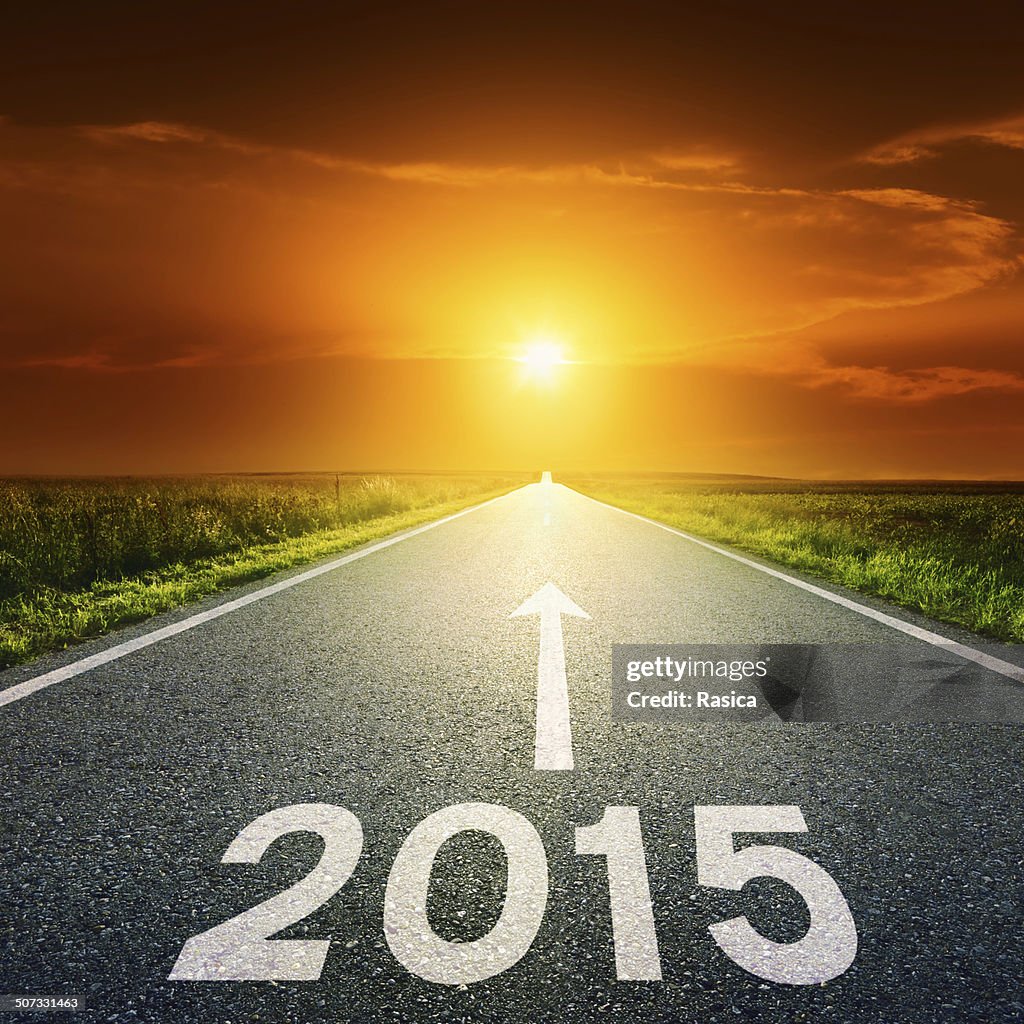 Driving on an empty road towards the sun to 2015