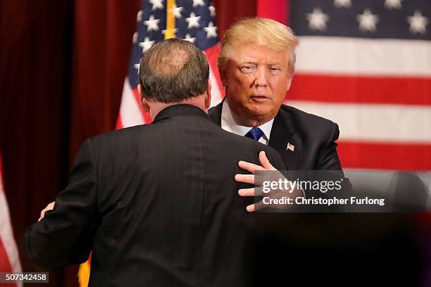 Republican presidential candidate Donald Trump embraces rival candidate Mike Huckabee during his rally for veterans at Drake University on January...