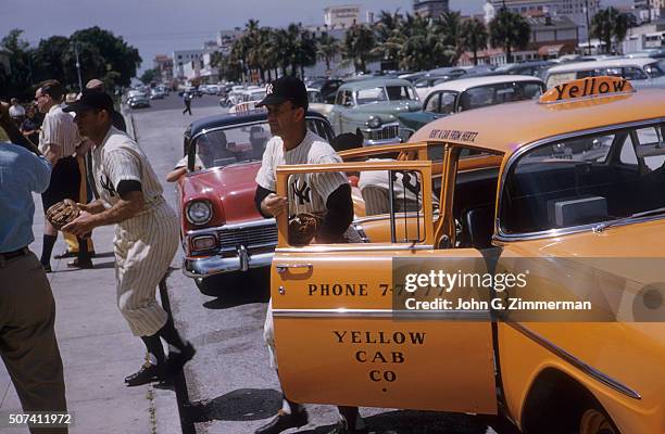 View of New York Yankees Enos Slaughter and Joe Collins exiting taxi in uniform outside of stadium before spring training game vs Milwaukee Braves at...