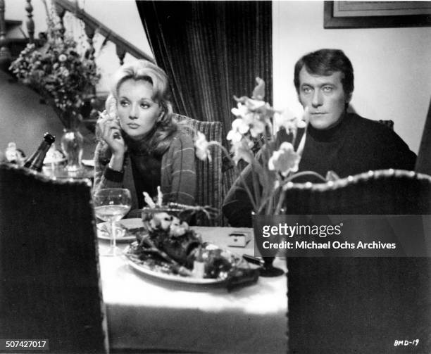 Caroline Cellier and Michel Duchaussoy look on at a dinner table in a scene from the movie "This Man Must Die" , circa 1969.