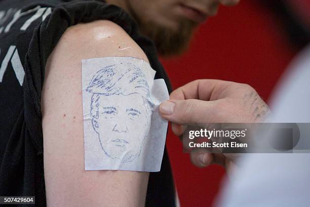 Bob Holmes, owner of The Clay Dragon Tattoo shop places a stencil of Republican presidential candidate on the arm of Seth Bailey in his shop on...