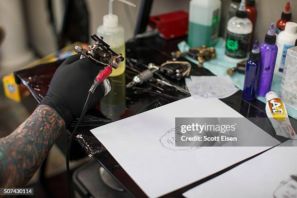 Bob Holmes, owner of the Clay Dragon Tattoo Shop puts more ink in his tattoo gun while tattooing a portrait of Republican presidential candidate...