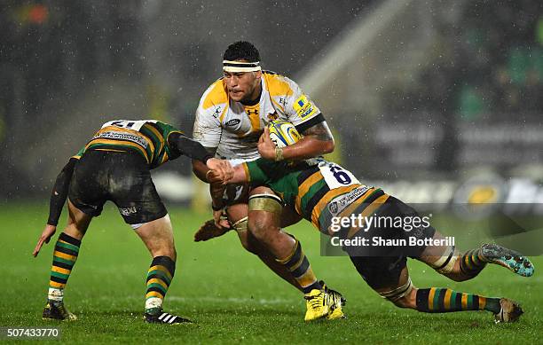 Nathan Hughes of Wasps is tackled by Lee Dickson of Northampton Saints and Tom Wood of Northampton Saints during the Aviva Premiership match between...