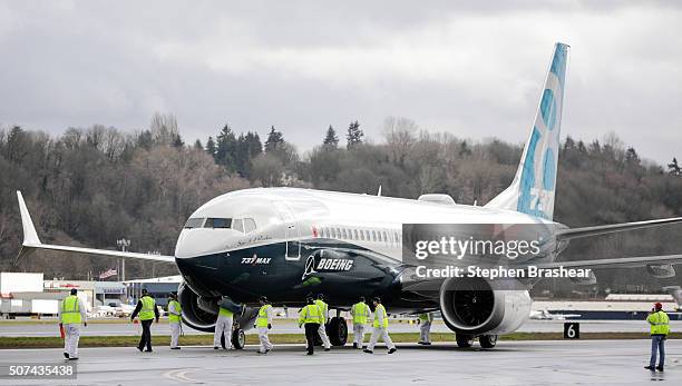 Members of the ground crew check out a Boeing 737 MAX 8 airliner after it landed at Boeing Field to complete its first flight on January 29, 2016 in...