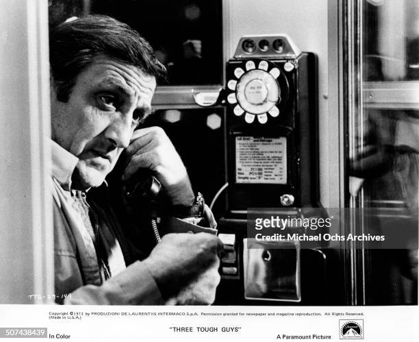 Lino Ventura makes a crucial phone call for outside help in a scene from the Paramount Pictures movie "Three Tough Guys", circa 1974.