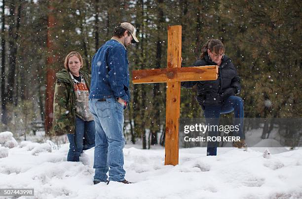 Mourners stand near a wooden cross on Highway 395 near Burns, Oregon on January 29 at the location where Robert "LaVoy" Finicum was shot dead and...