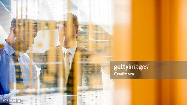 two managers shot through glass wall - wealth manager stock pictures, royalty-free photos & images