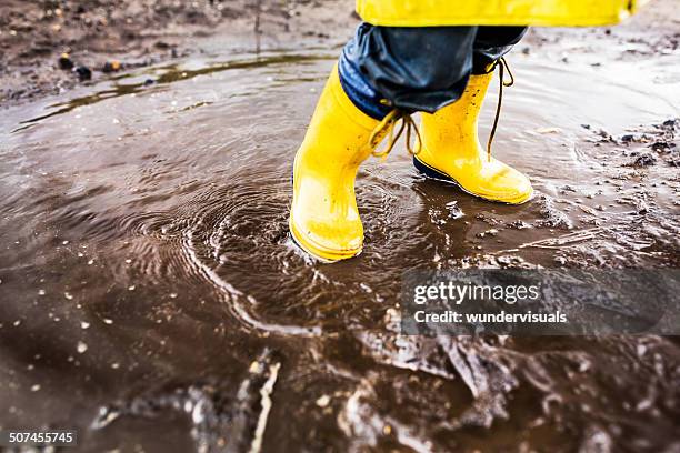 yellow rainboots in puddle - yellow boot stock pictures, royalty-free photos & images