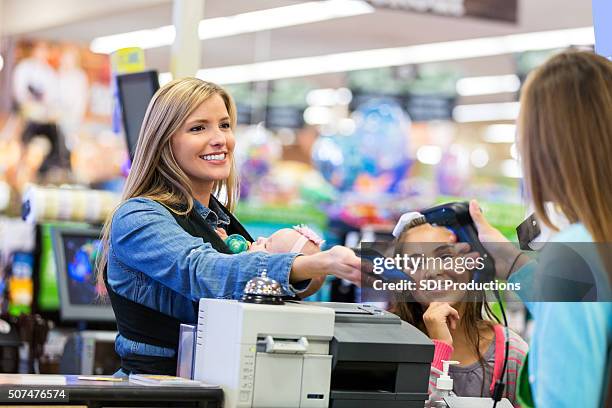 madre utilizzando smartphone per pagare acquisti effettuati in negozio - paying supermarket foto e immagini stock