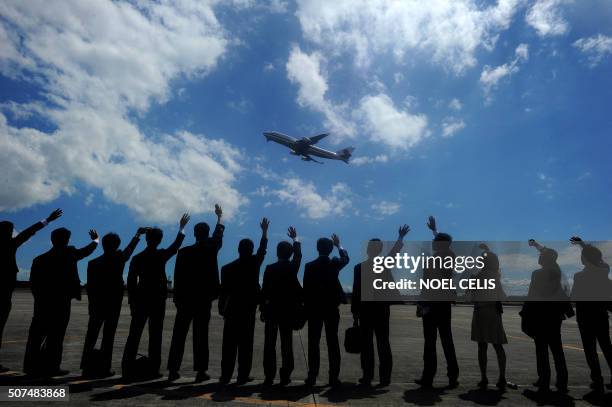 Personnel from the Japanese embassy wave to the plane carrying Japan's Emperor Akihito and Empress Michiko as they depart from the Villamor Airbase...