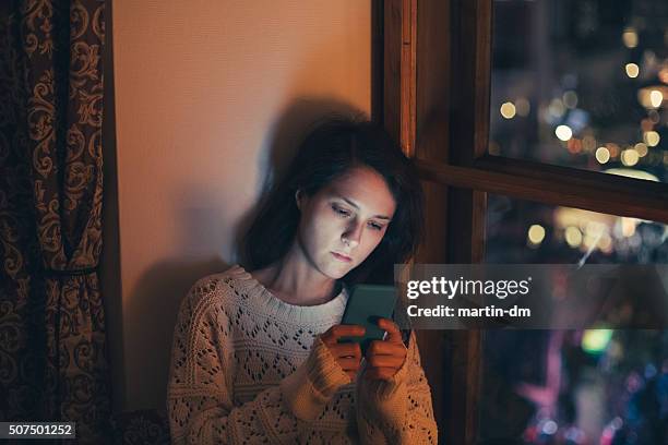 sad woman texting at home - depressie landelement stockfoto's en -beelden