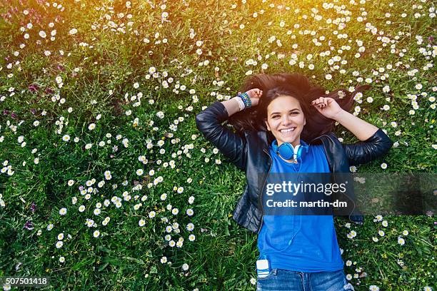 smiling teenage girl lying down in the grass - girl lying down stock pictures, royalty-free photos & images