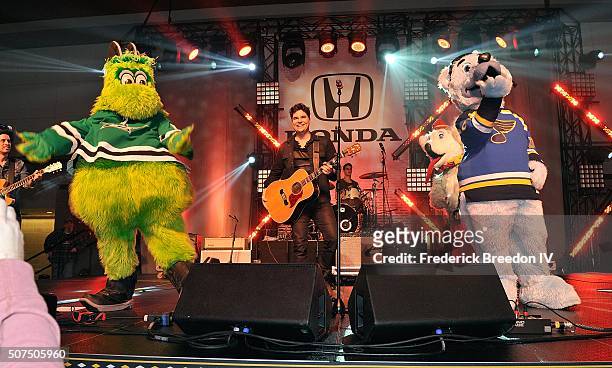 Steven Lee Olsen is joined on stage by NHL mascots Victor E. Green, of the Dallas Stars, and Louie, of the St. Louis during a performance on the...