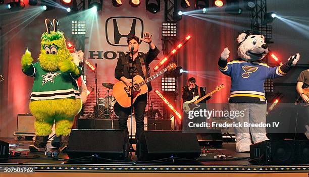 Steven Lee Olsen is joined on stage by NHL mascots Victor E. Green, of the Dallas Stars, and Louie, of the St. Louis during a performance on the...