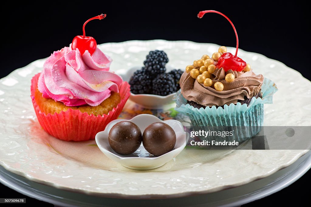 China plate with cupcakes, chocolate truffles and blackberries