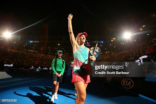 Angelique Kerber of Germany holds the Daphne Akhurst Trophy and waves to the crowd at Rod Laver Arena after winning the Women's Singles Final against...