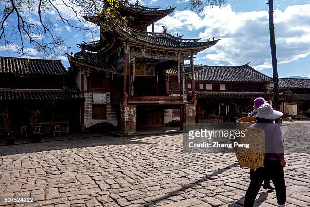 Local people walk past the ancient theatrical stage in the center of Sideng market square. The Sideng market square of Shaxi was added to the World...