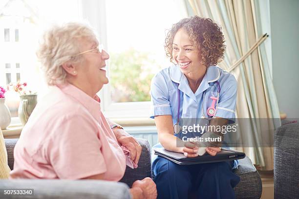 freundliche krankenschwester besuch bei einer familie - pflegedienst blau stock-fotos und bilder