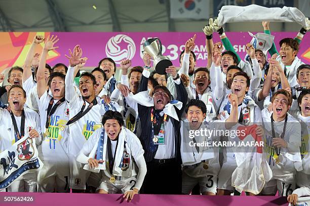Japan's head coach Makoto Teguramori carries the trophy as he celebrates with his players following the AFC U23 Championship final football match...
