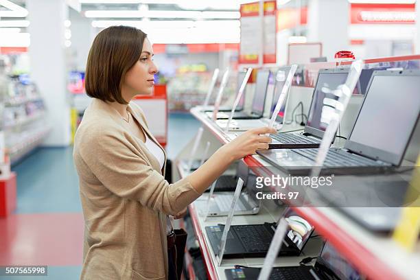woman chooses the laptop - electrical shop stock pictures, royalty-free photos & images