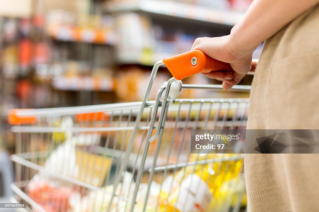 Femme avec panier d'achat dans un supermarché