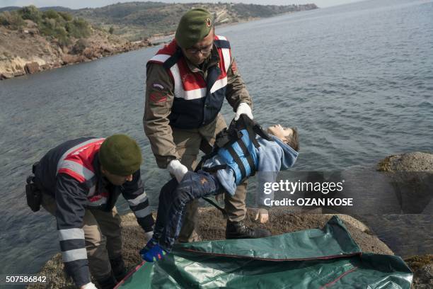 Graphic content / Turkish gendarmes put the body of a child into a body bag on a beach in Canakkale's Bademli district on January 30, 2016 after at...