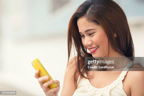 giovane donna usando il suo smartphone - filipino ethnicity foto e immagini stock