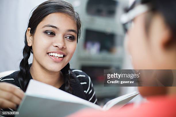 over shoulder view of happy indian girl students discussing. - hand turning page stock pictures, royalty-free photos & images