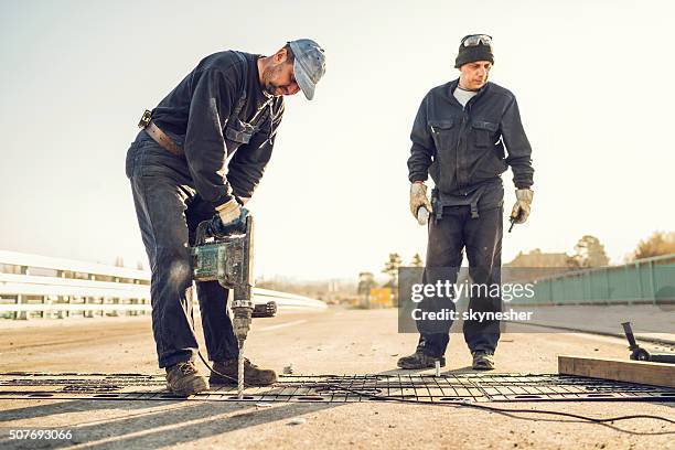 trabalhador da construção civil consertar ponte com um exercício. - broca imagens e fotografias de stock