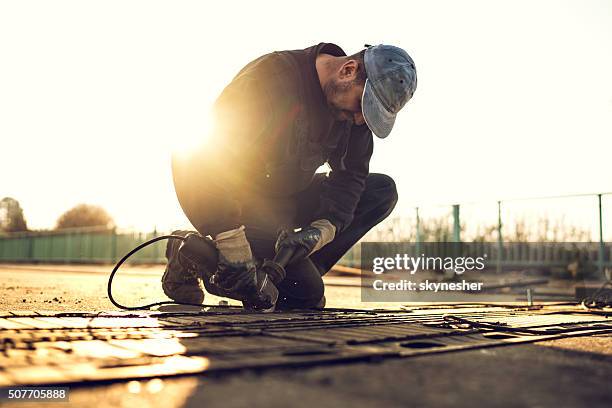 construction worker on road maintenance at sunset. - elektrisch gereedschap stockfoto's en -beelden