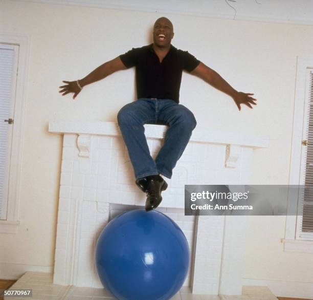 Actor Steve Harris sitting atop his fireplace mantle at home.