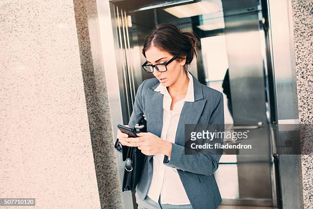 geschäftsfrau sms auf den aufzug - aufzug business stock-fotos und bilder