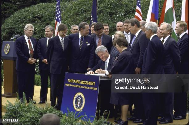 Pres. Bill Clinton putting pen to paper during White House Nato expansion signing ceremony, State Secy. Madeleine Albright & VP Al Gore among...