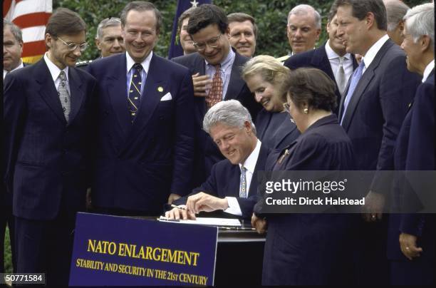 Pres. Bill Clinton putting pen to paper during White House Nato expansion signing ceremony, State Secy. Madeleine Albright & VP Al Gore among...