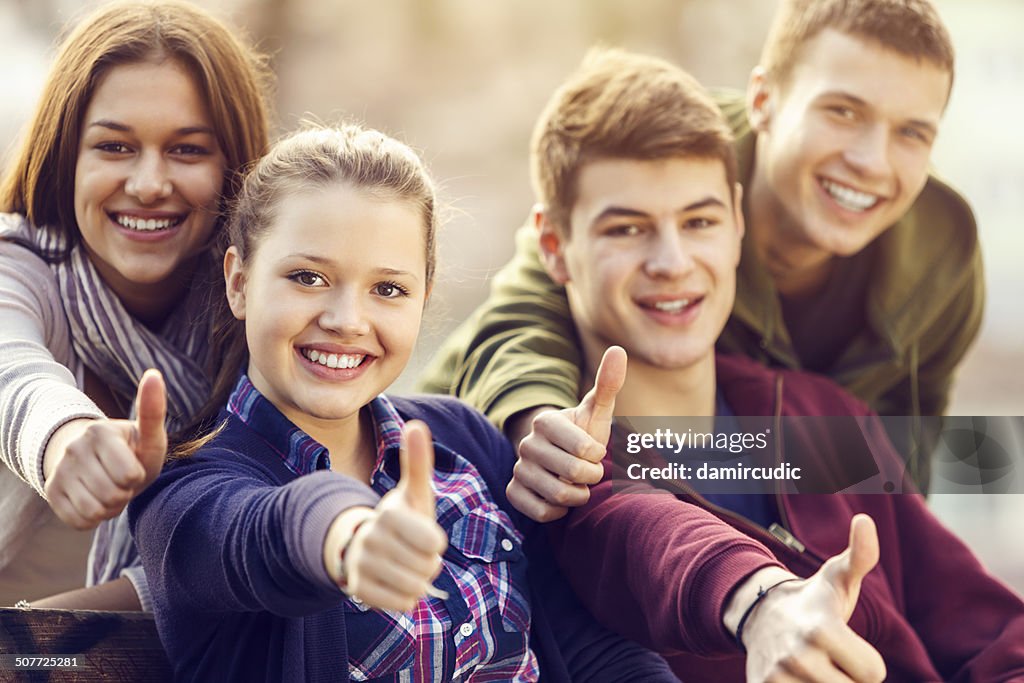 Grupo de amigos de adolescente feliz mostrando os polegares para cima