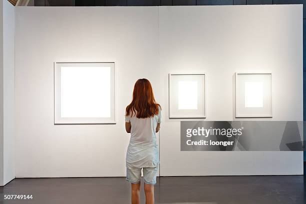 une femme regarde monture blanc dans une galerie d'art - person spot light photos et images de collection