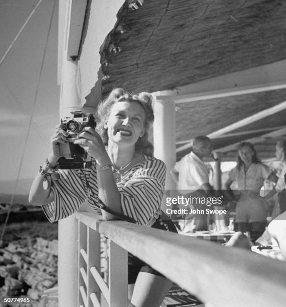 Ariane Allen, third wife of Harold Ross, editor of The New Yorker, holding camera while vacationing on French Riviera.