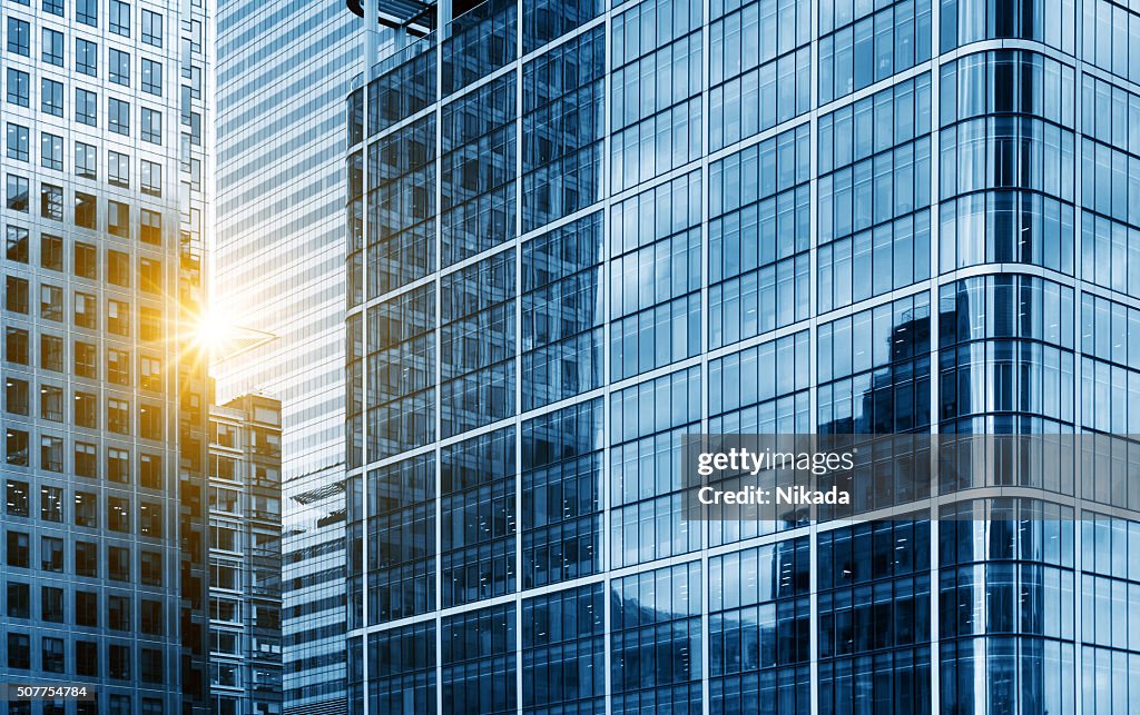 View of a contemporary glass skyscraper reflecting the blue sky