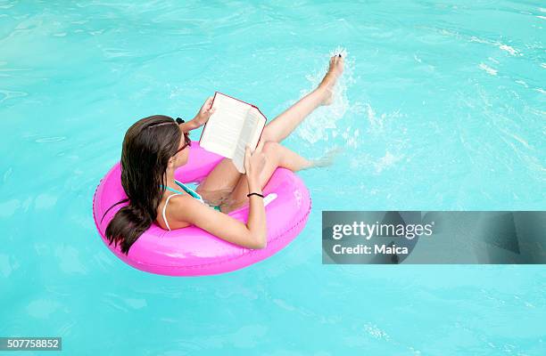 kinder lesen und entspannen auf einem rosa lebensretter - beach book reading stock-fotos und bilder