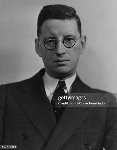 An employee of the Farm Security Administration , wearing a suit and glasses, poses for a portrait, 1935. From the New York Public Library. .