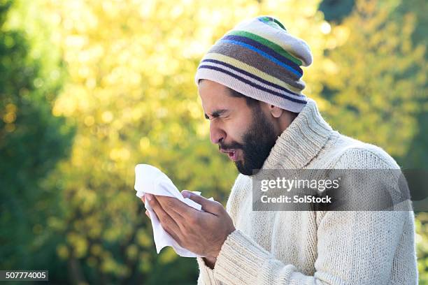 asian man sneezing into tissue - sneezing stockfoto's en -beelden