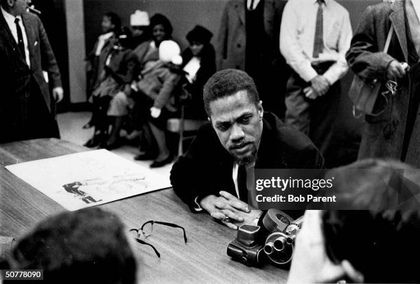 Malcolm X at press conference, JFK airport, upon returning from Africa. Betty Shabazz and four daughters are in rear.