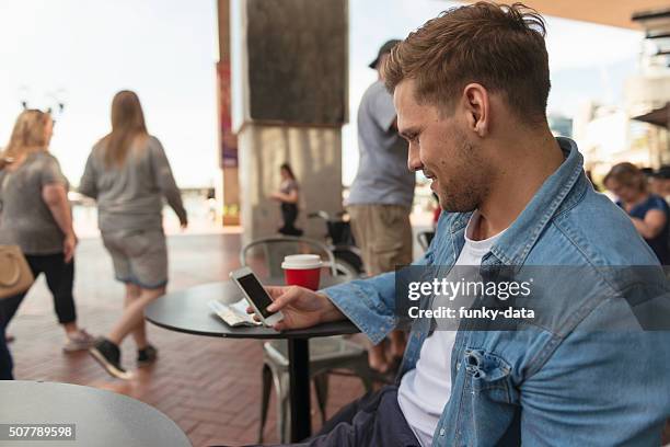 hombre joven verificar mensajes - darling harbor fotografías e imágenes de stock