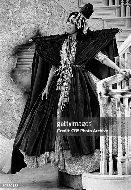 In a scene from 'The Carol Burnett Show,' American comedienne and actress Carol Burnett descends a staircase, dressed in dress made from a window...