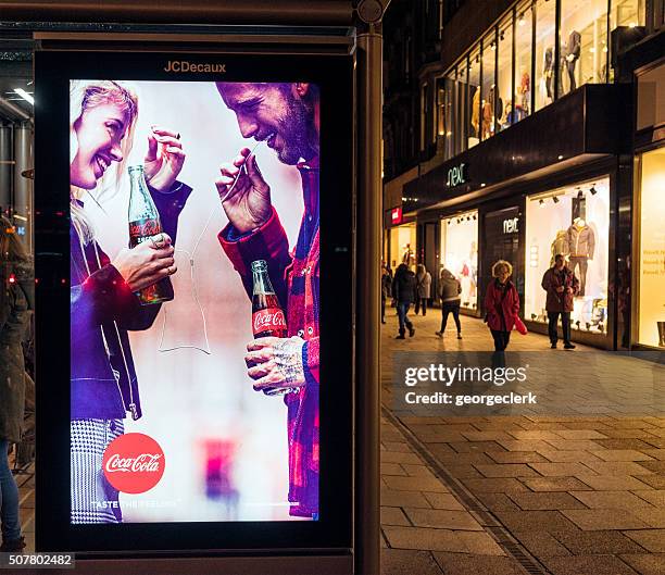 beleuchtete coca-cola-werbung bei nacht - jcdecaux stock-fotos und bilder