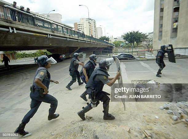 Riot police take cover behind their shields during skirmishes with supporters of Venezuelan President Hugo Chavez in Caracas, 28 April, 2004. The...